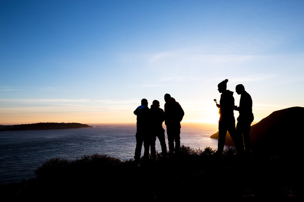 people on bank of sea with sunrise sky - Фото, зображення