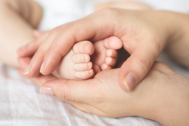 Pieds de bébé dans les mains de la mère
 - Photo, image