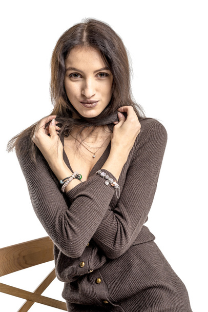 Beautiful brunette girl posing on a chair in a long sweater and woolen stockings - Valokuva, kuva