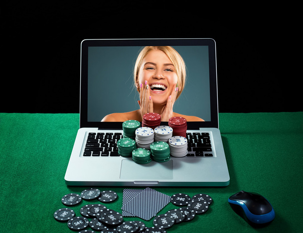 Casino chips en kaarten op toetsenbord notebook aan groene tafel. - Foto, afbeelding