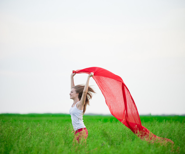 Jonge dame runing met weefsel in groene veld. Vrouw met sjaal. - Foto, afbeelding