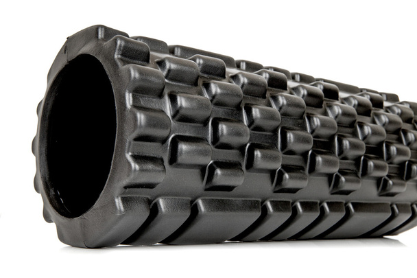 A black bumpy foam massage roller. Foam rolling is a self-myofascial release technique that is used by athletes and physical therapists to inhibit overactive muscles. - Photo, Image