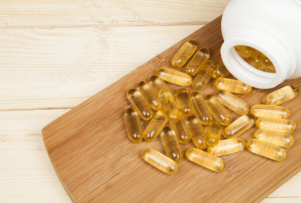 Cod liver oil omega 3 gel capsules on the wooden table desk isolated on white background on top - Foto, Imagen
