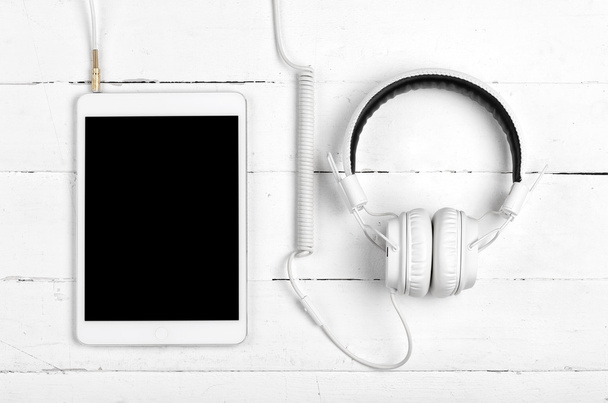 Valkoinen tabletti kuulokkeilla
 - Valokuva, kuva