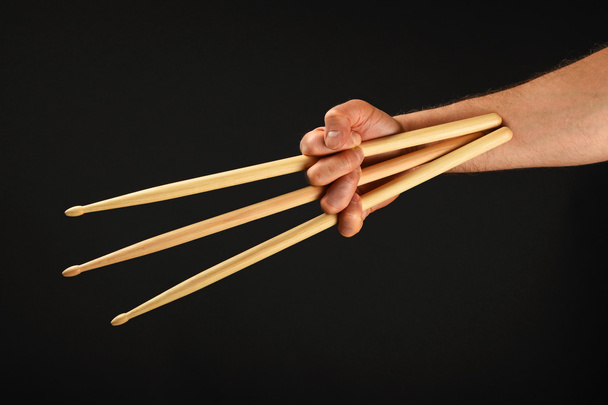 Рука росомахи с тремя барабанными палочками на черном
 - Фото, изображение