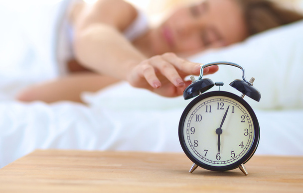 Young sleeping woman and alarm clock in bedroom at home - Foto, Imagem