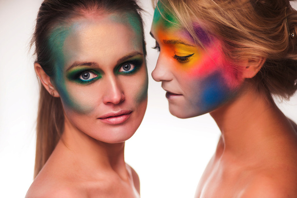 Kosmické krásy. Portrét dvou krásných žen nosí umělecký make-up pózuje s peří bílé pozadí - Fotografie, Obrázek