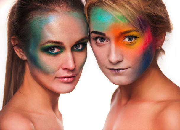 Космічна краса. Портрет двох красивих жінок у художньому макіяжі, що позує з пір'ям на білому тлі
 - Фото, зображення
