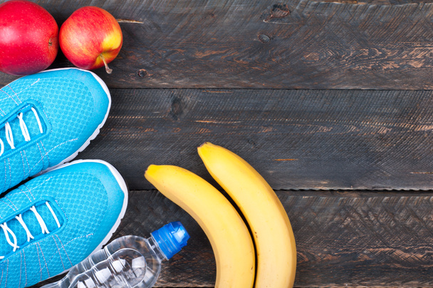 Sport and healthy life. Sport shoes, apples, bananas and bottle  - Photo, Image