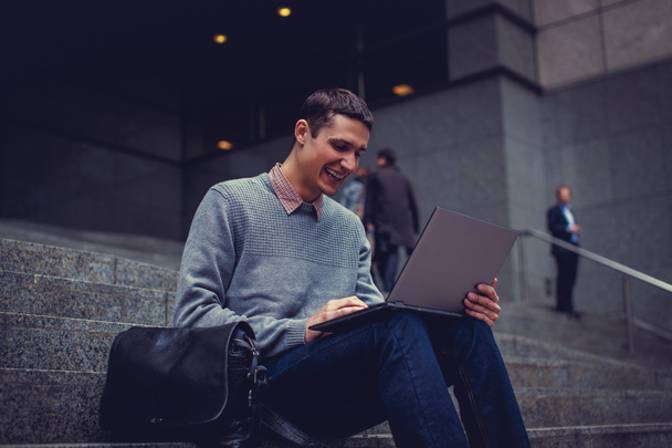 hymyilevä nuori mies kannettavan tietokoneen kanssa
 - Valokuva, kuva