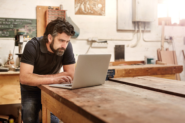 designer working on laptop on workbench in studio - Zdjęcie, obraz