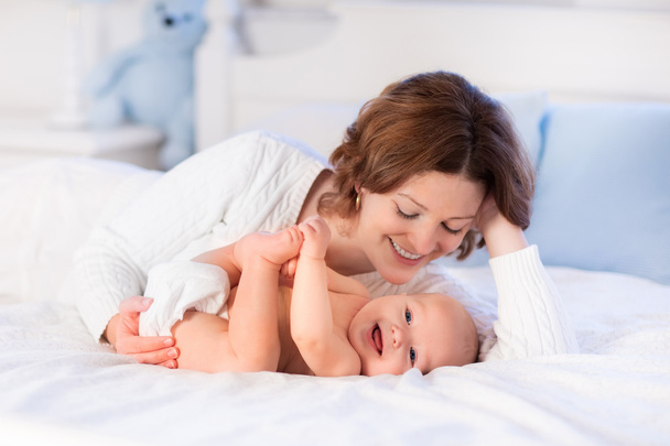 Mãe e bebê em uma cama branca
 - Foto, Imagem