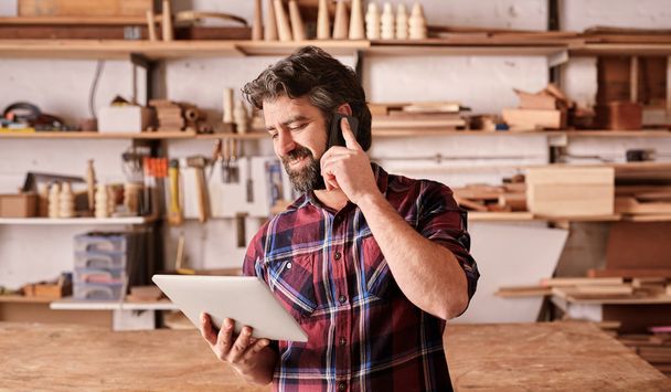 carpenter using mobile and holding tablet - Photo, image