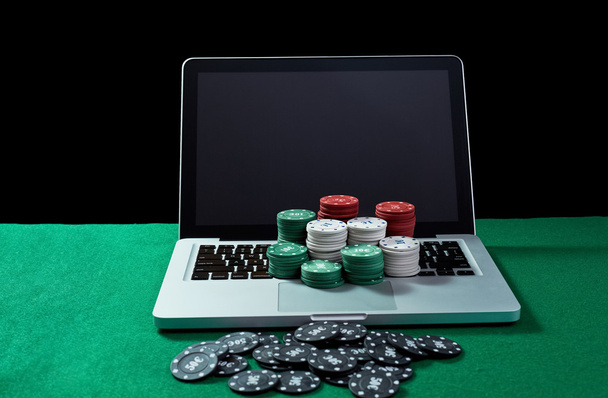 Casino chips on keyboard notebook at green table. - Zdjęcie, obraz