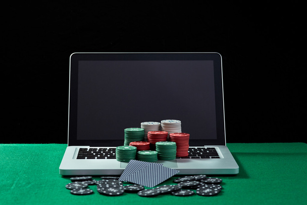 Casino chips and cards on keyboard notebook at green table. - Photo, Image