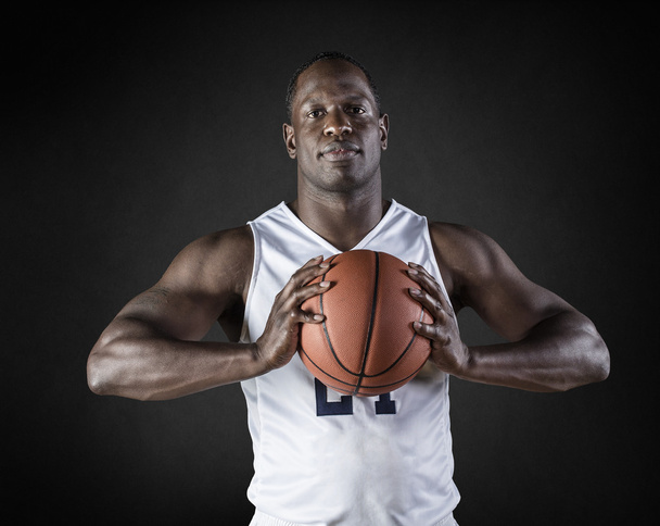 Portrait d'un joueur afro-américain de basket tenant une balle. Fond noir
 - Photo, image