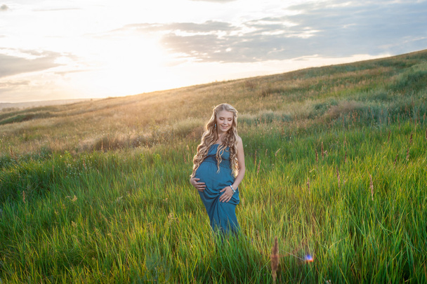 Bella donna incinta tenera in piedi su erba verde
 - Foto, immagini