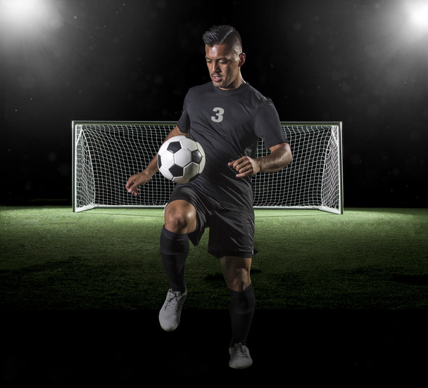 Giocatore di calcio ispanico che gioca a calcio su uno sfondo scuro
 - Foto, immagini