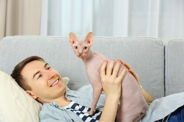 Handsome man lies with cat on couch - Foto, Imagem