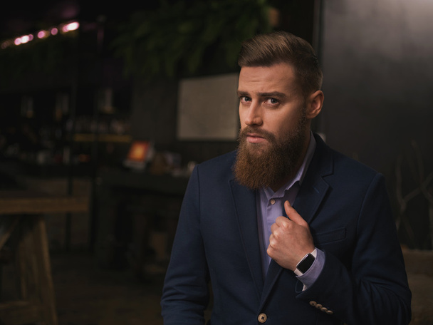 Cheerful young businessman with beard in cafe - Фото, изображение