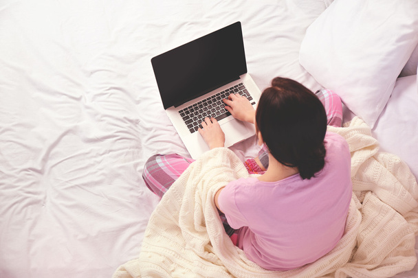 Woman in pajamas using laptop  - Фото, изображение
