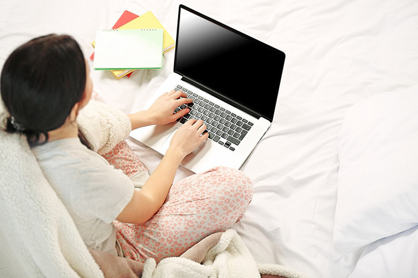 Woman in pajamas using laptop  - Fotó, kép