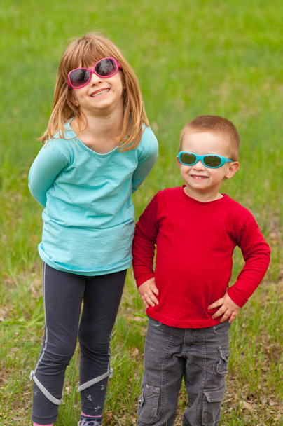 Bruder und Schwester posieren draußen mit Sonnenbrille auf den Augen an einem schönen Frühlingstag - Foto, Bild