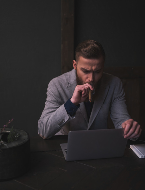 Привабливий бородатий чоловік працює з ноутбуком
 - Фото, зображення