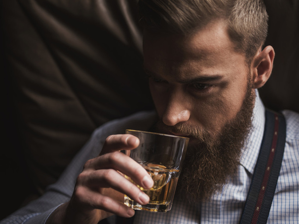 Cheerful bearded businessman is drinking expensive whisky - Фото, зображення