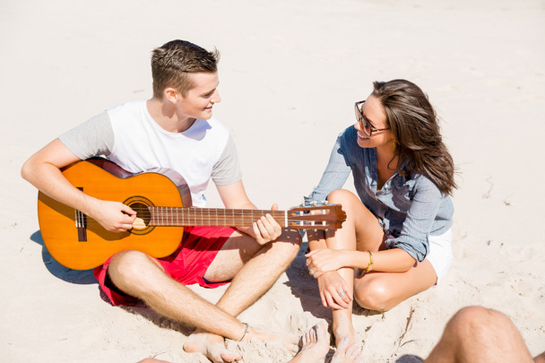 Beautiful young people with guitar on beach - Fotó, kép