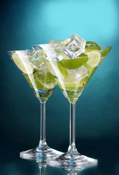 Glasses of cocktails with lime and mint on blue background - Photo, Image