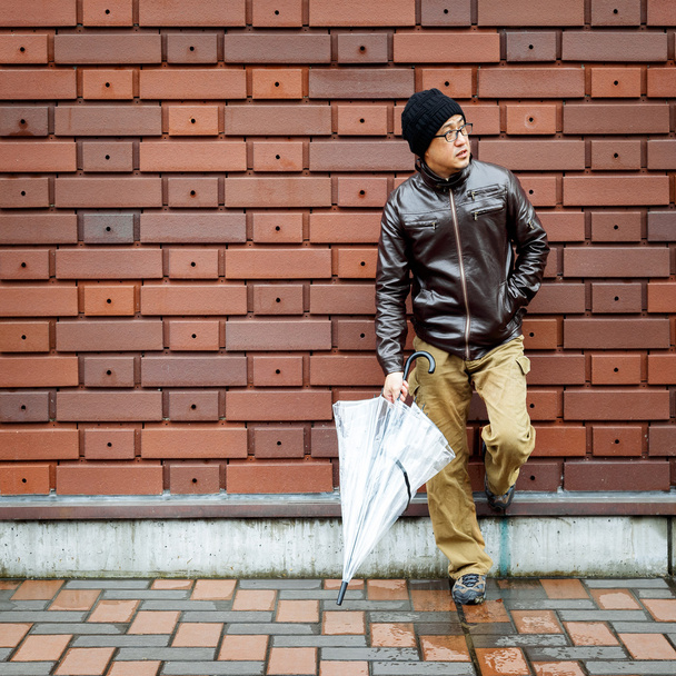 Un hombre asiático en una chaqueta marrón con un paraguas claro
 - Foto, Imagen