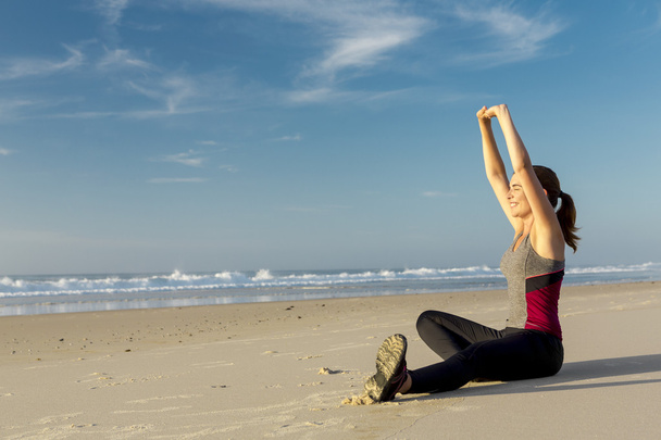 Woman making stretching exercises in the beach - Photo, image