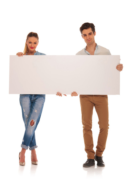 casual couple posing holding a blank billboard - Фото, зображення