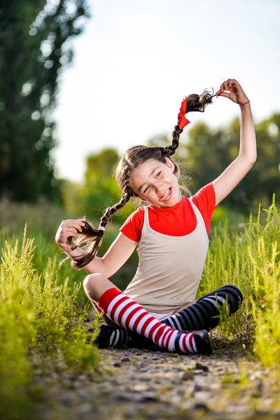 дівчина з кісками уявляє літо на природі
 - Фото, зображення