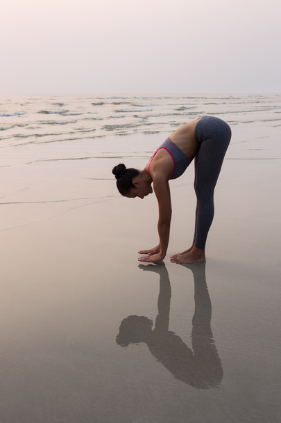 Jeune femme mince pratiquant la pose du yoga sur la plage au coucher du soleil
 - Photo, image