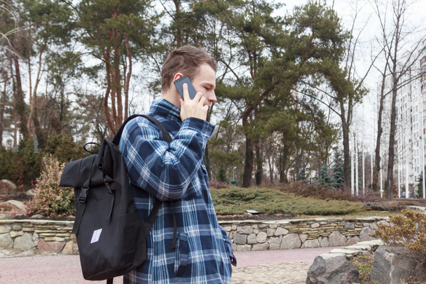 ο τύπος στην πόλη με ένα σακίδιο που μιλάει στο τηλέφωνο - Φωτογραφία, εικόνα