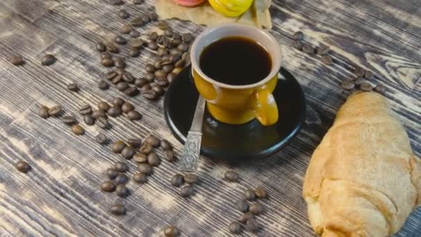 Café y croissant y macarones girando sobre mesa de madera
 - Imágenes, Vídeo