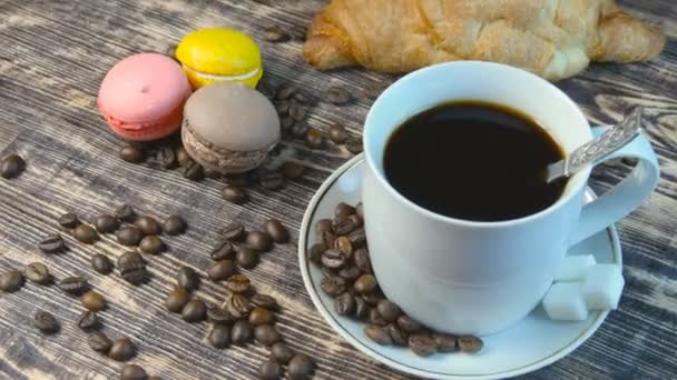 Kahvi ja Croissant ja Macarones pyörivät puinen pöytä - Materiaali, video