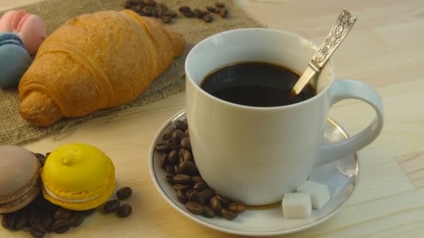 Koffie, croissantje en macarones draaien op houten tafel - Video