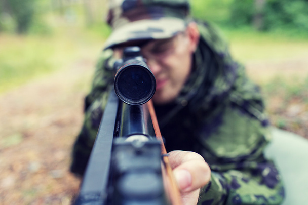 close up of soldier or hunter with gun in forest - Фото, изображение