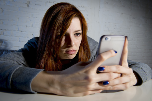 young sad vulnerable girl using mobile phone scared and desperate suffering online abuse cyberbullying - Foto, afbeelding