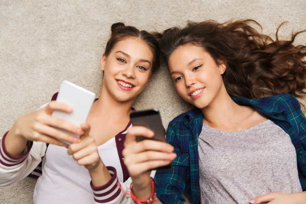 happy teenage girls lying on floor with smartphone - Photo, image