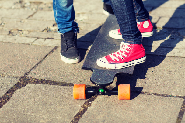close up of couple with longboard on street - Foto, Imagem