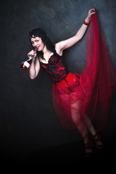 Happy Beautiful brunette woman in corset and long hair with bottle of wine - Фото, изображение