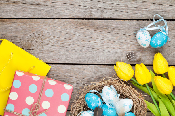 Пасхальні яйця на фоні гнізда та подарунок
 - Фото, зображення
