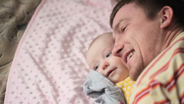 Ευτυχής πατέρας παίζοντας με την κόρη του μωρού στο κρεβάτι στο υπνοδωμάτιο - Πλάνα, βίντεο