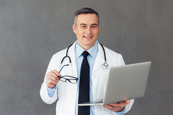 Mature male doctor with laptop - 写真・画像