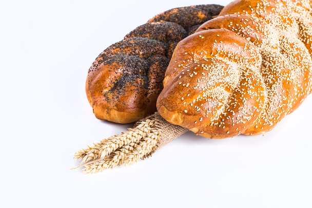 Two whole fresh challah bread with poppy and sesame seeds on a w - Foto, afbeelding