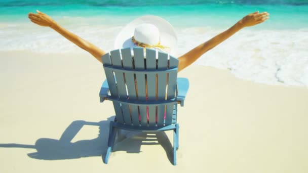Dziewczyna, opalając się na drewnianym krześle na tropikalnej plaży  - Materiał filmowy, wideo